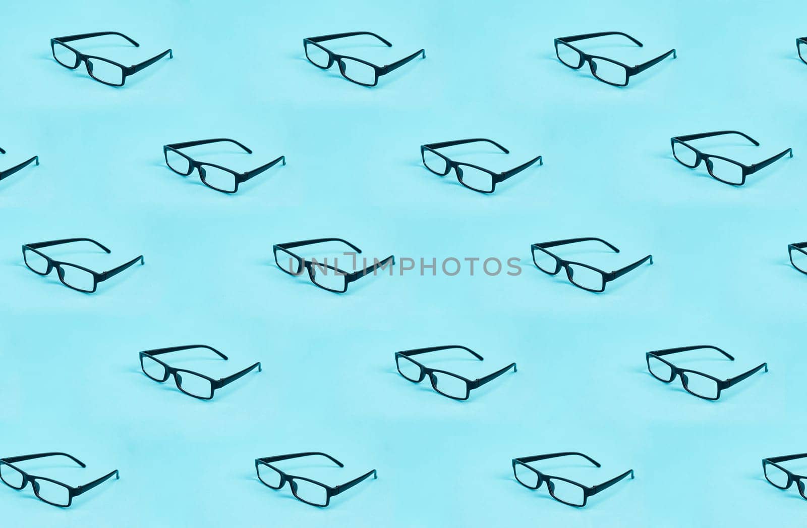 Many eyeglasses with a black frame on a blue background, copy space for text