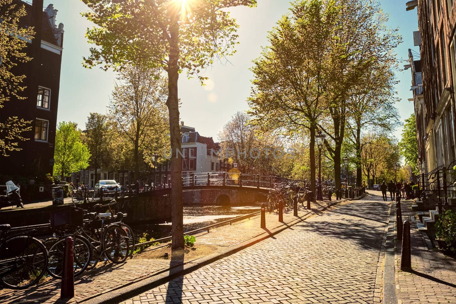 Amsterdam street with canal and old houses and bicycle on sunset. Amsterda, Netherlands