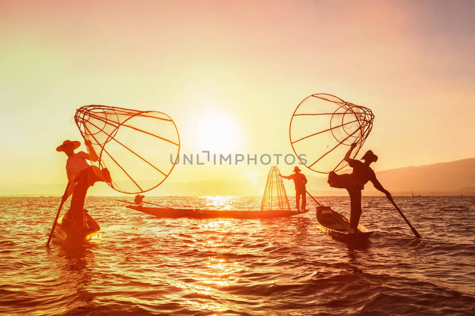 Myanmar travel attraction landmark - three traditional Burmese fishermen at Inle lake, Myanmar famous for their distinctive one legged rowing style