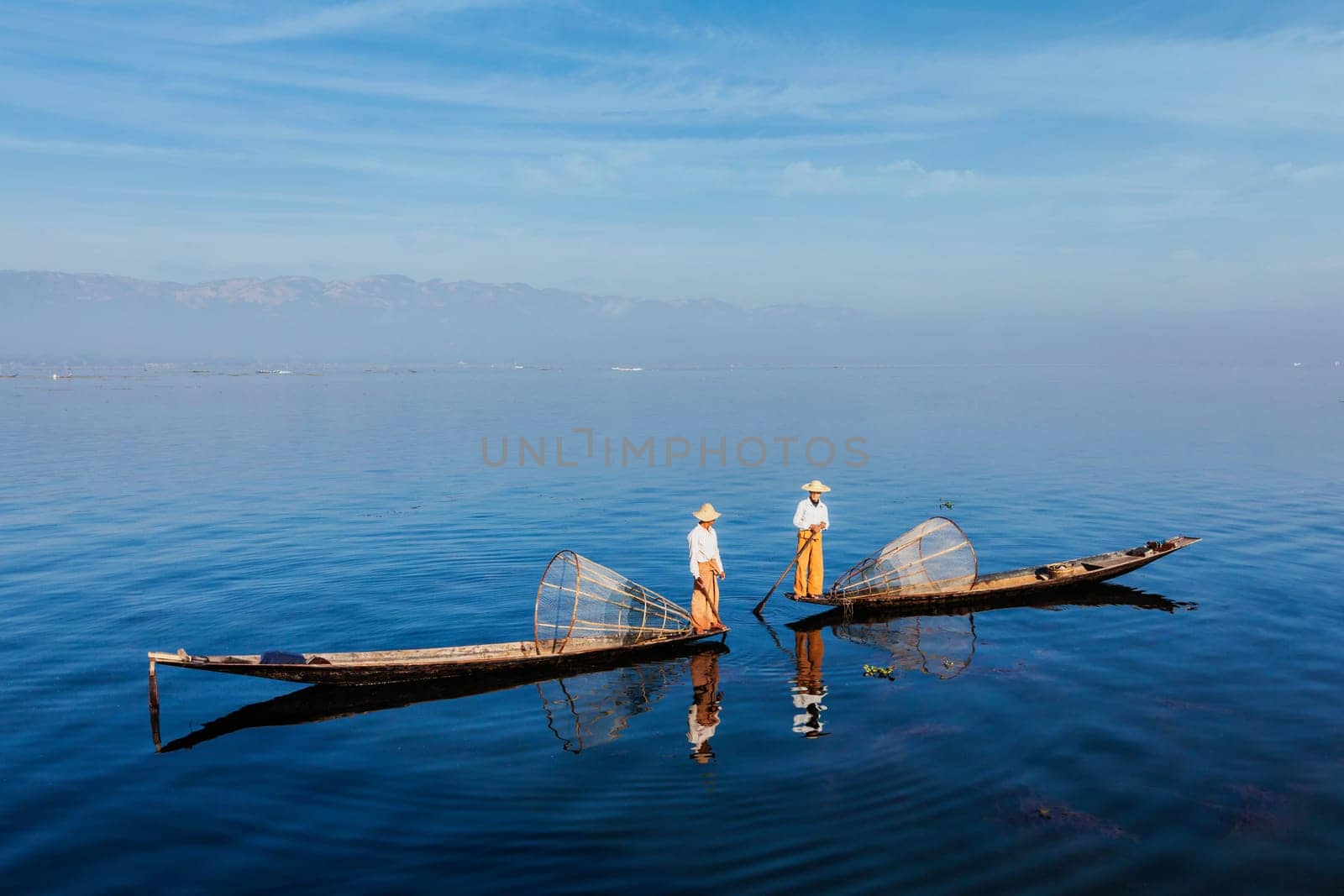 Myanmar travel attraction landmark - Traditional Burmese fishermen with fishing net at Inle lake in Myanmar famous for their distinctive one legged rowing style