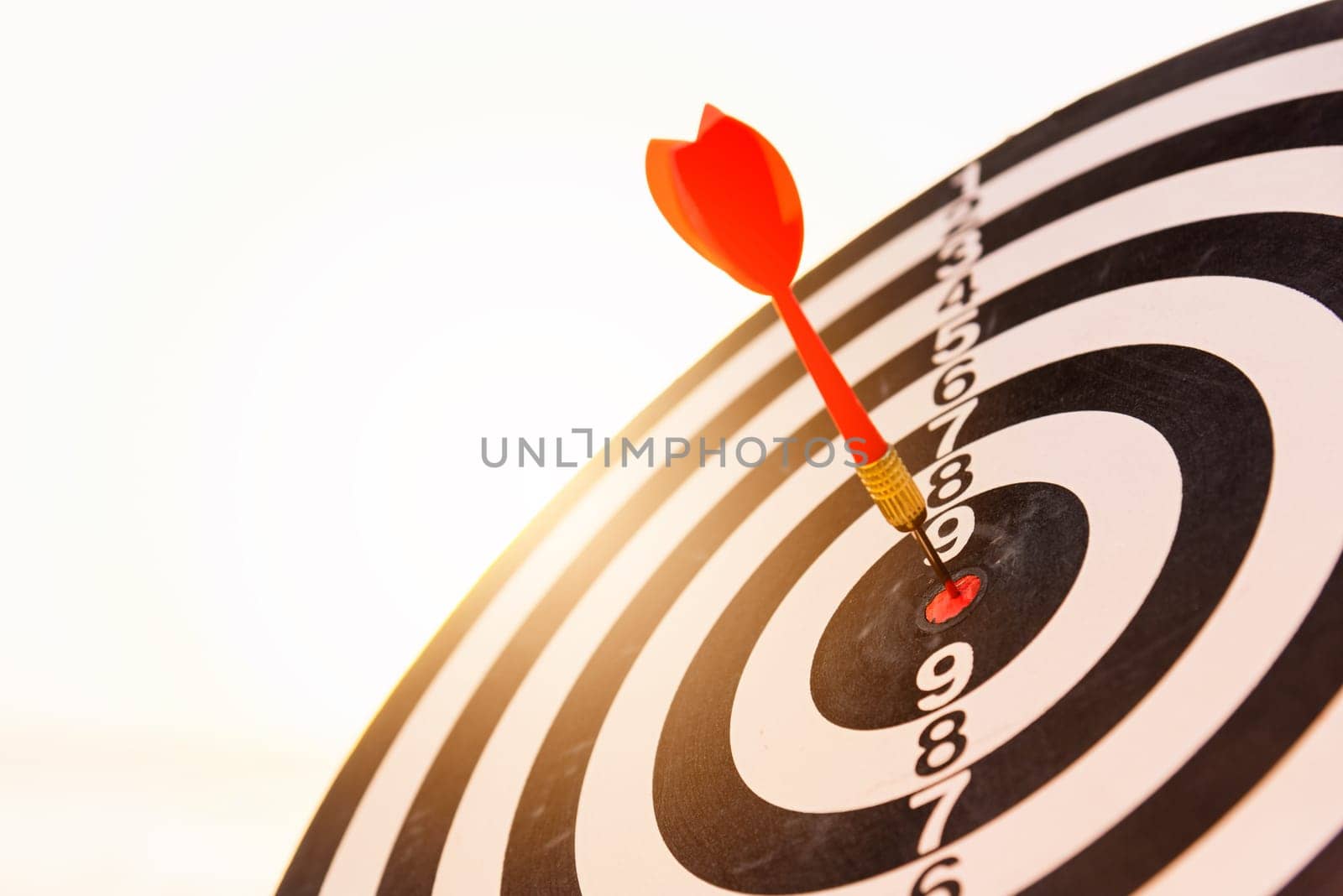 Dart arrow hit to center on bullseye(bull's-eye) of a dartboard is a target of purpose challenge business at sunset, expert strategy market target, objective financial and goal a concept