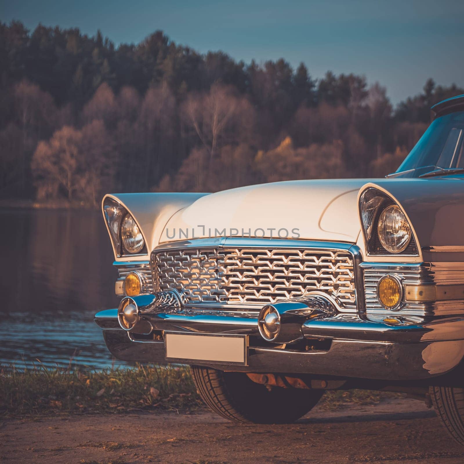 Old retro or vintage car or automobile front side with front lights or headlights and radiator grill on the lake. Processed by vintage or retro effect filter