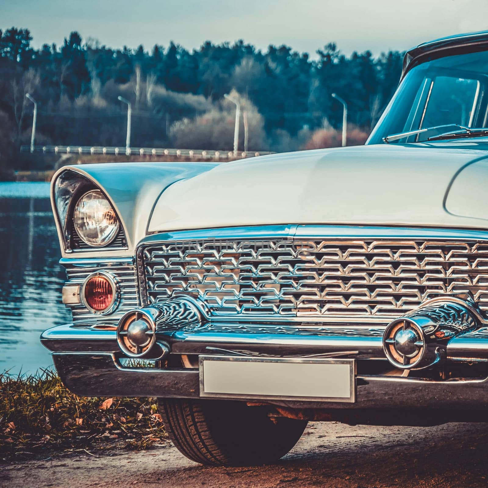 Old retro or vintage car or automobile front side with front lights or headlights and radiator grill on the lake. Processed by vintage or retro effect filter