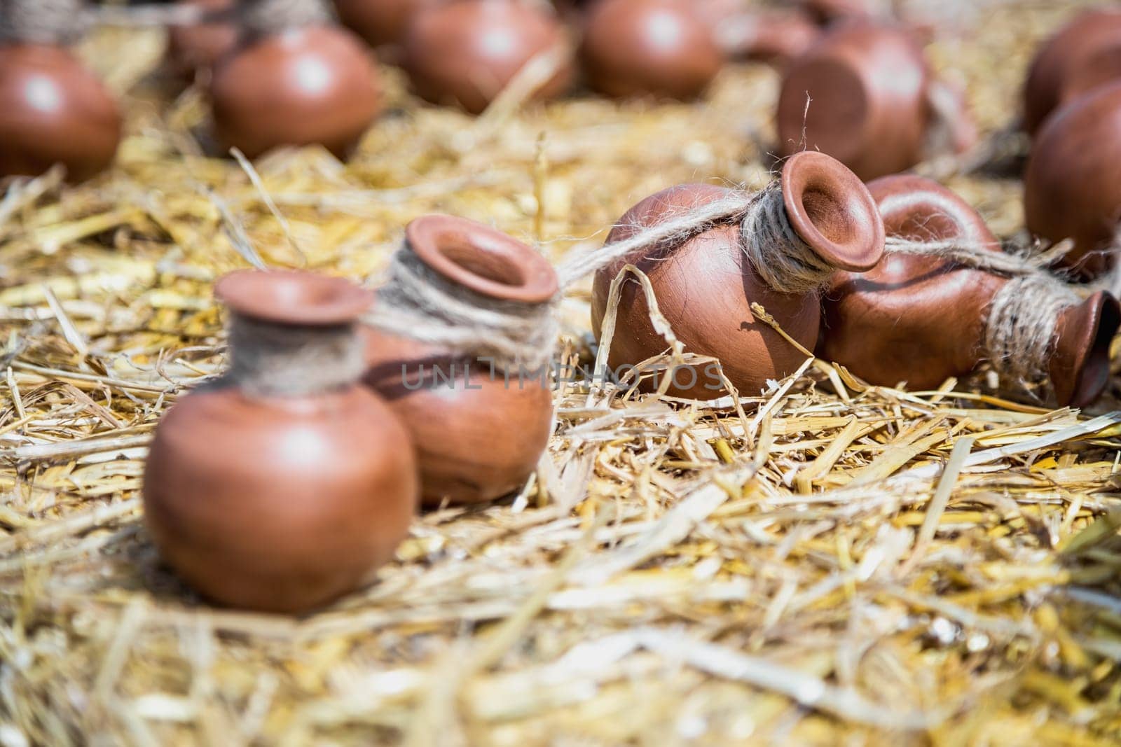 Small ceramic crocks or pot countryside decoration or souvenir on straw. Selective focus of image on one of crock