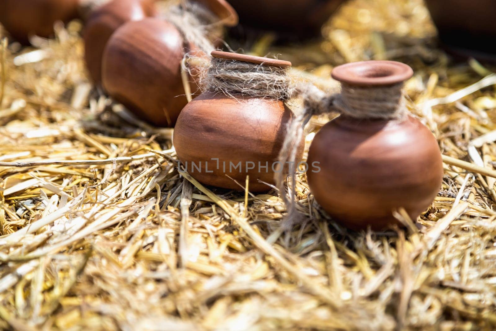 Small ceramic crocks or pot countryside decoration or souvenir on straw. Selective focus of image on one of crock