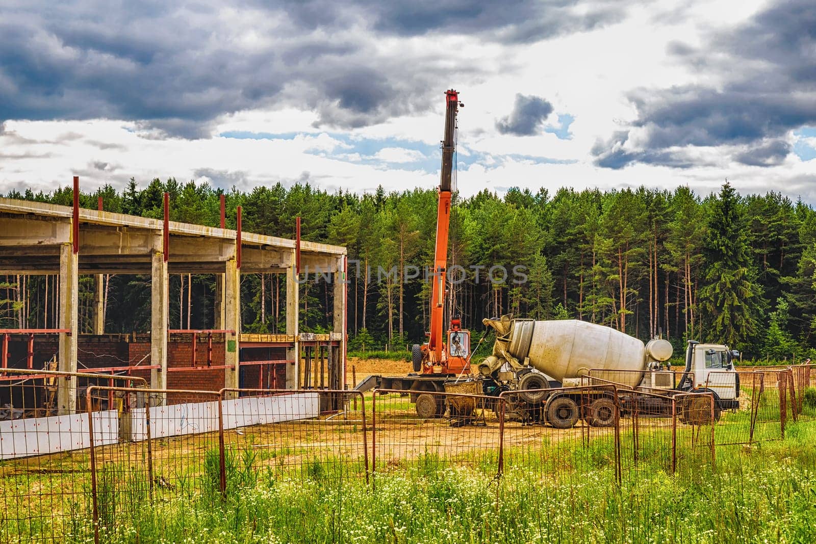 Building under construction at a construction site with crane and concrete mixer. Processed by hdr effect filter