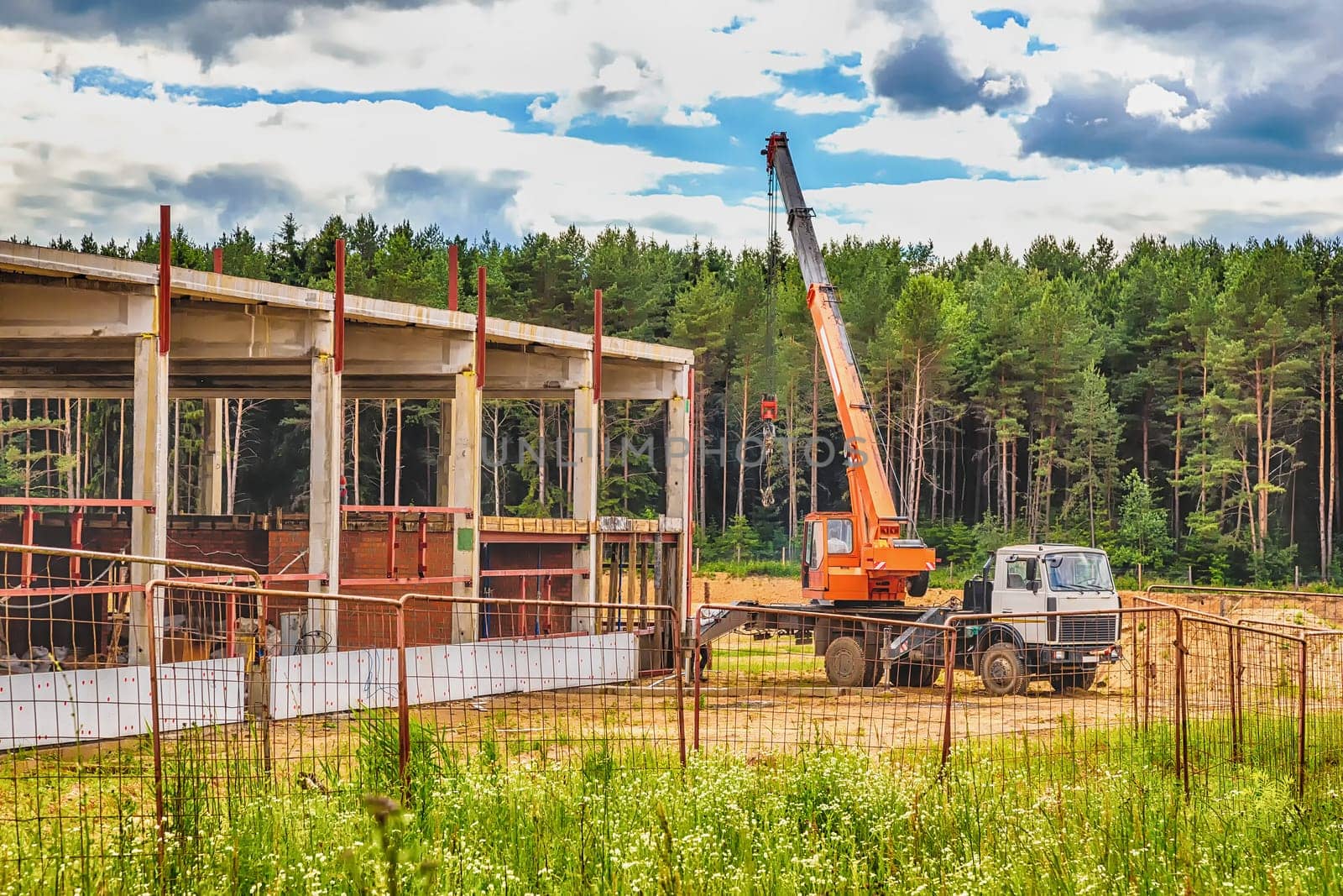 Building under construction at a construction site with a truck and a crane. Processed by hdr effect filter