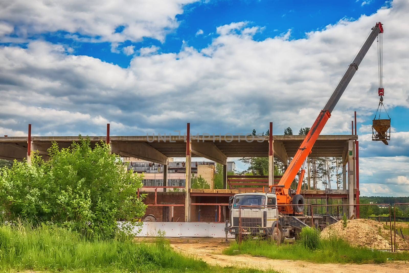 Building under construction at a construction site with a truck and a crane. Processed by hdr effect filter