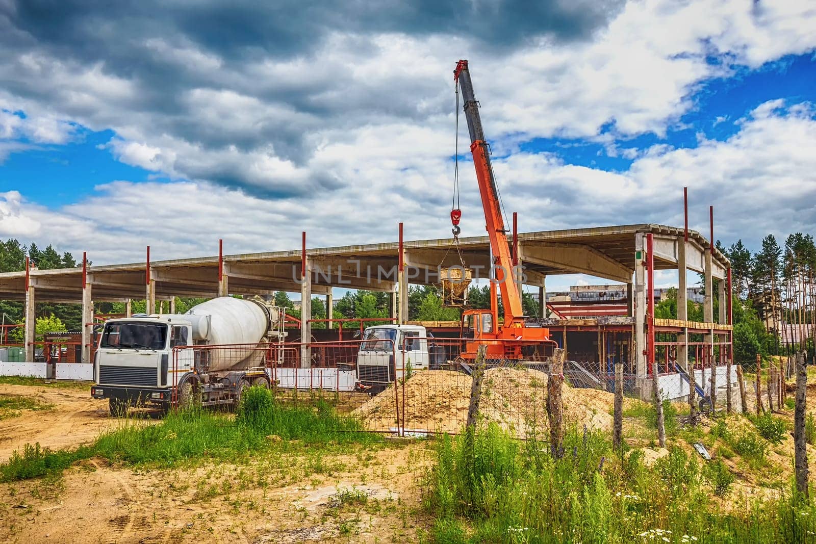 Building under construction at a construction site with crane and concrete mixer. Processed by hdr effect filter