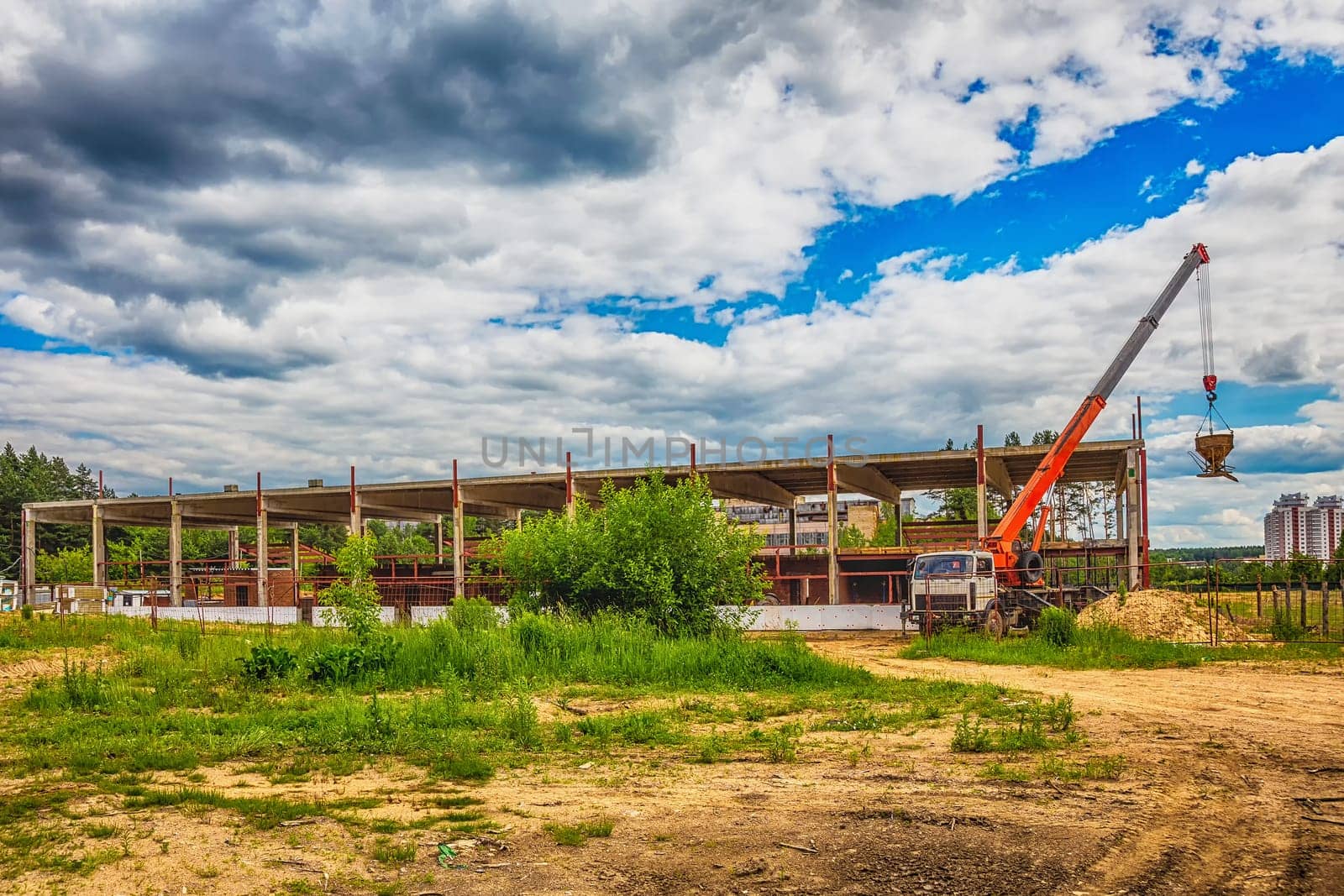 Building under construction at a construction site with a truck and a crane. Processed by hdr effect filter