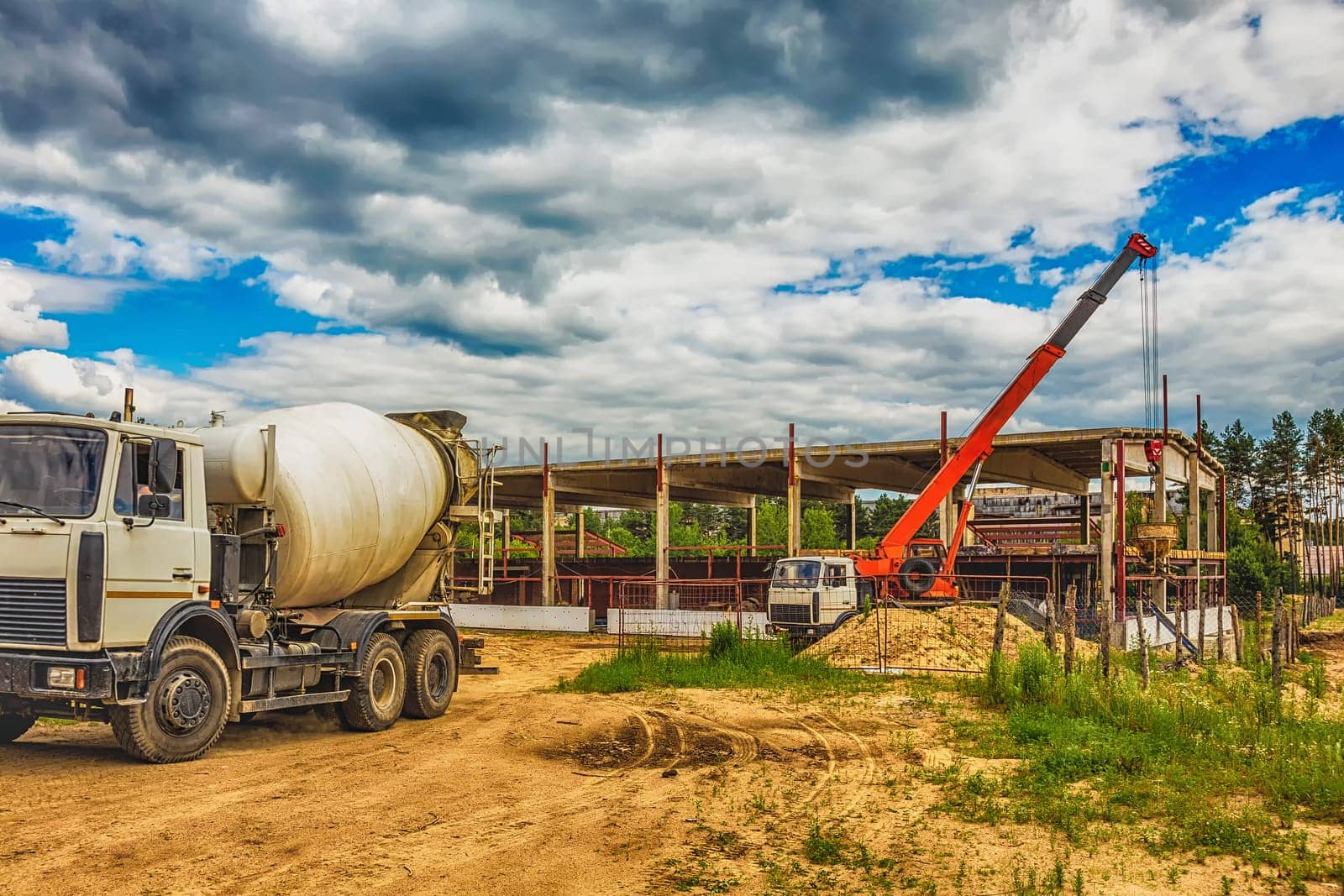 Building under construction at a construction site with crane and concrete mixer. Processed by hdr effect filter