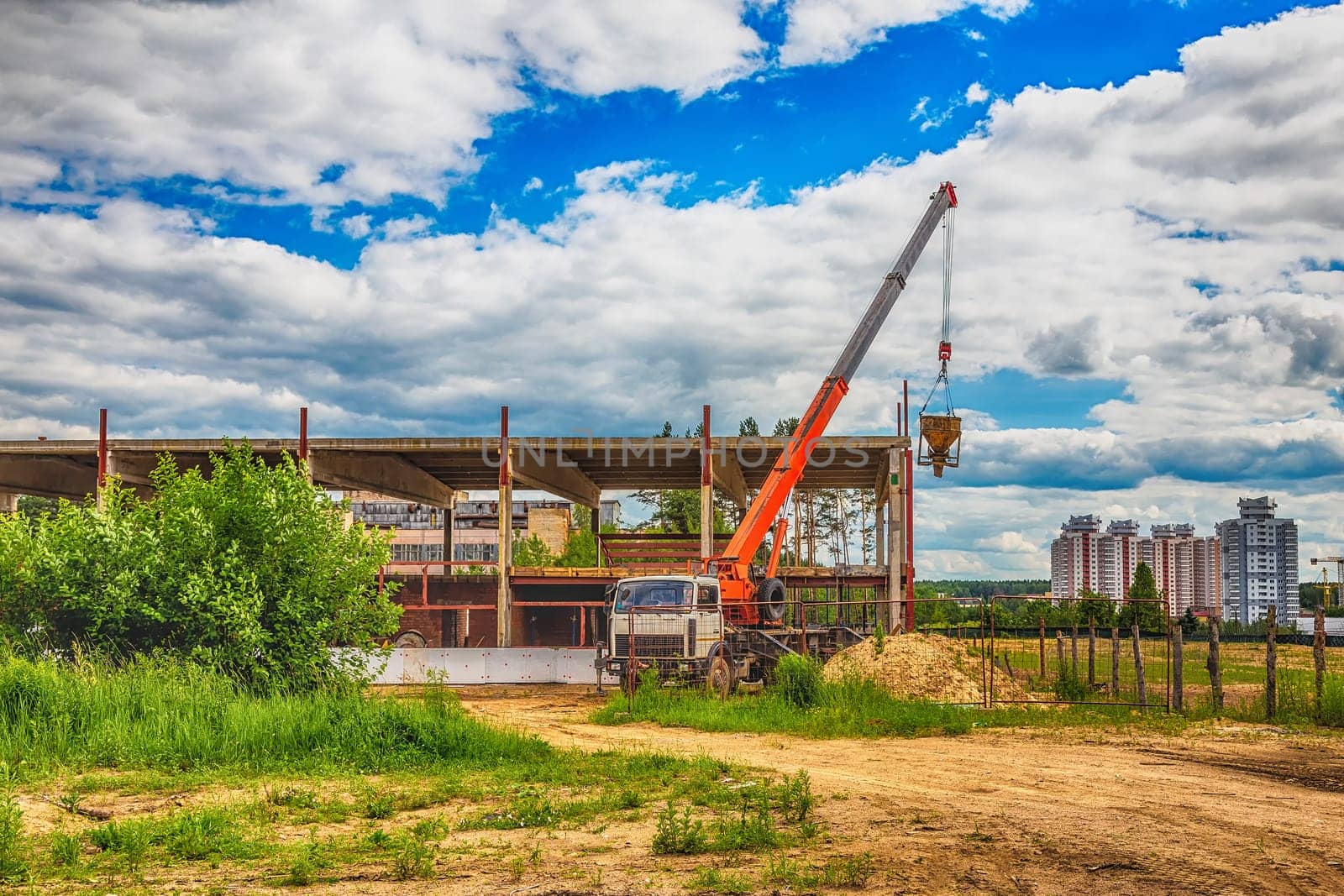 Building under construction at a construction site with a truck and a crane. Processed by hdr effect filter