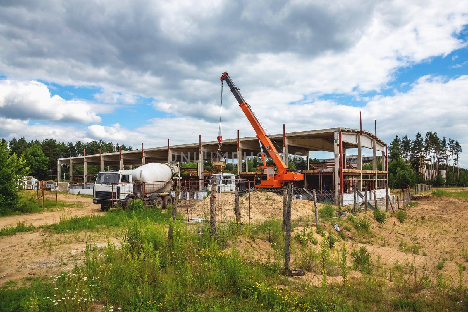 Building under construction at a construction site with crane and concrete mixer