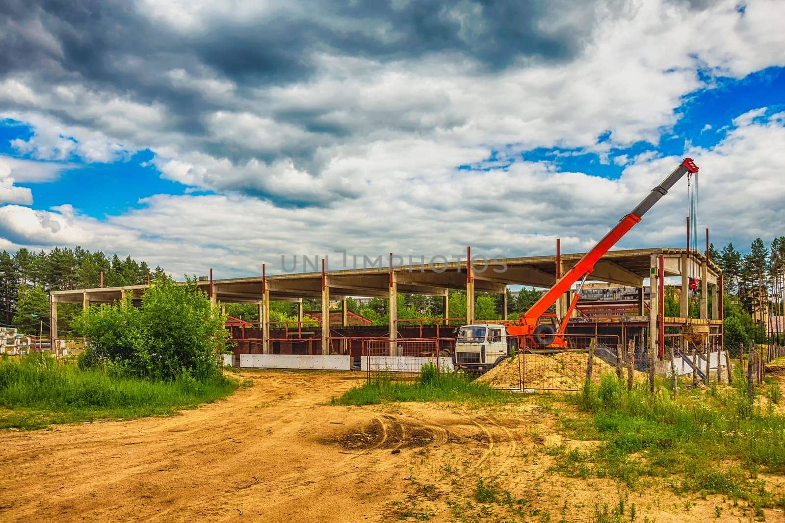 Building under construction at a construction site with a truck and a crane. Processed by hdr effect filter