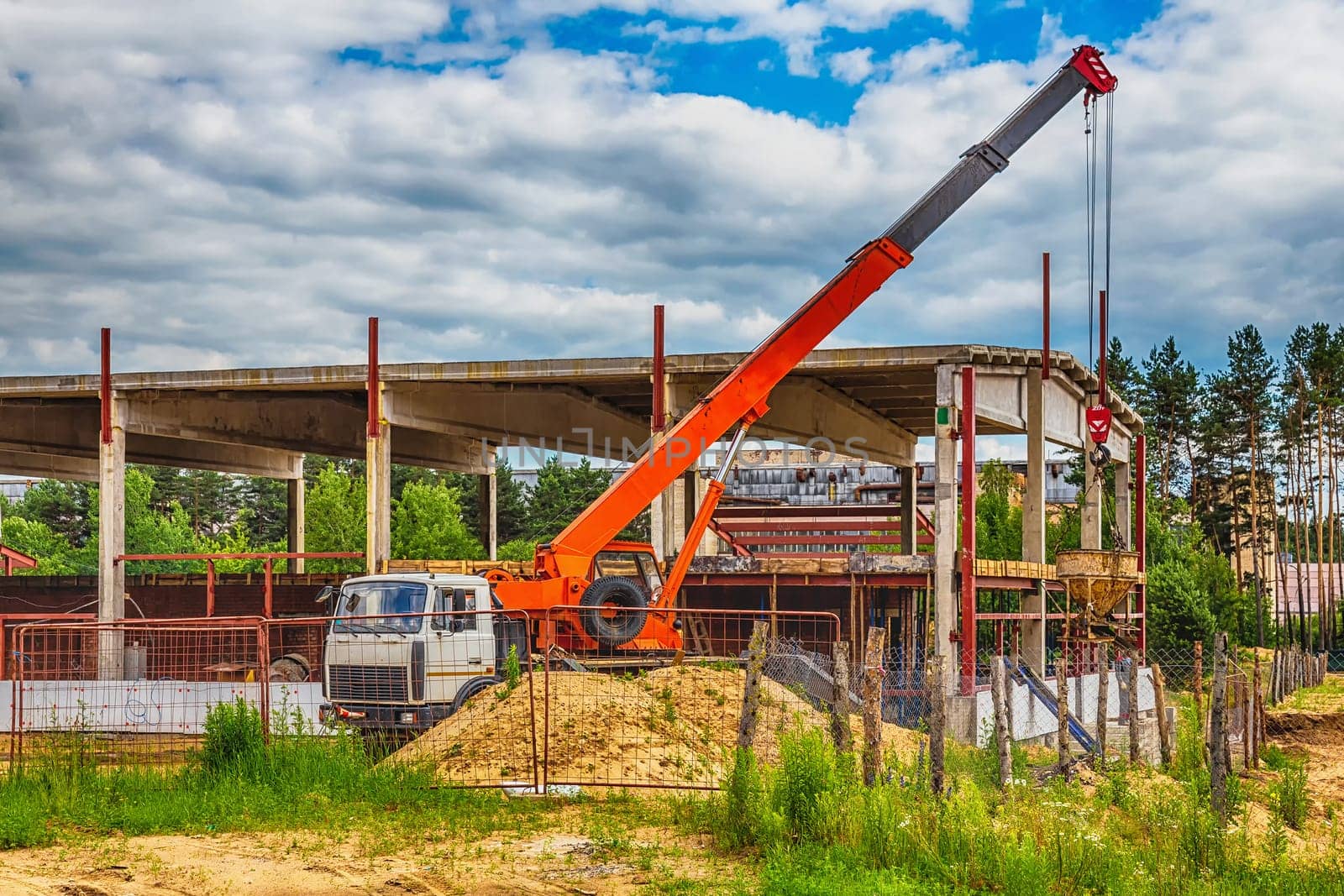 Building under construction at a construction site with a truck and a crane. Processed by hdr effect filter