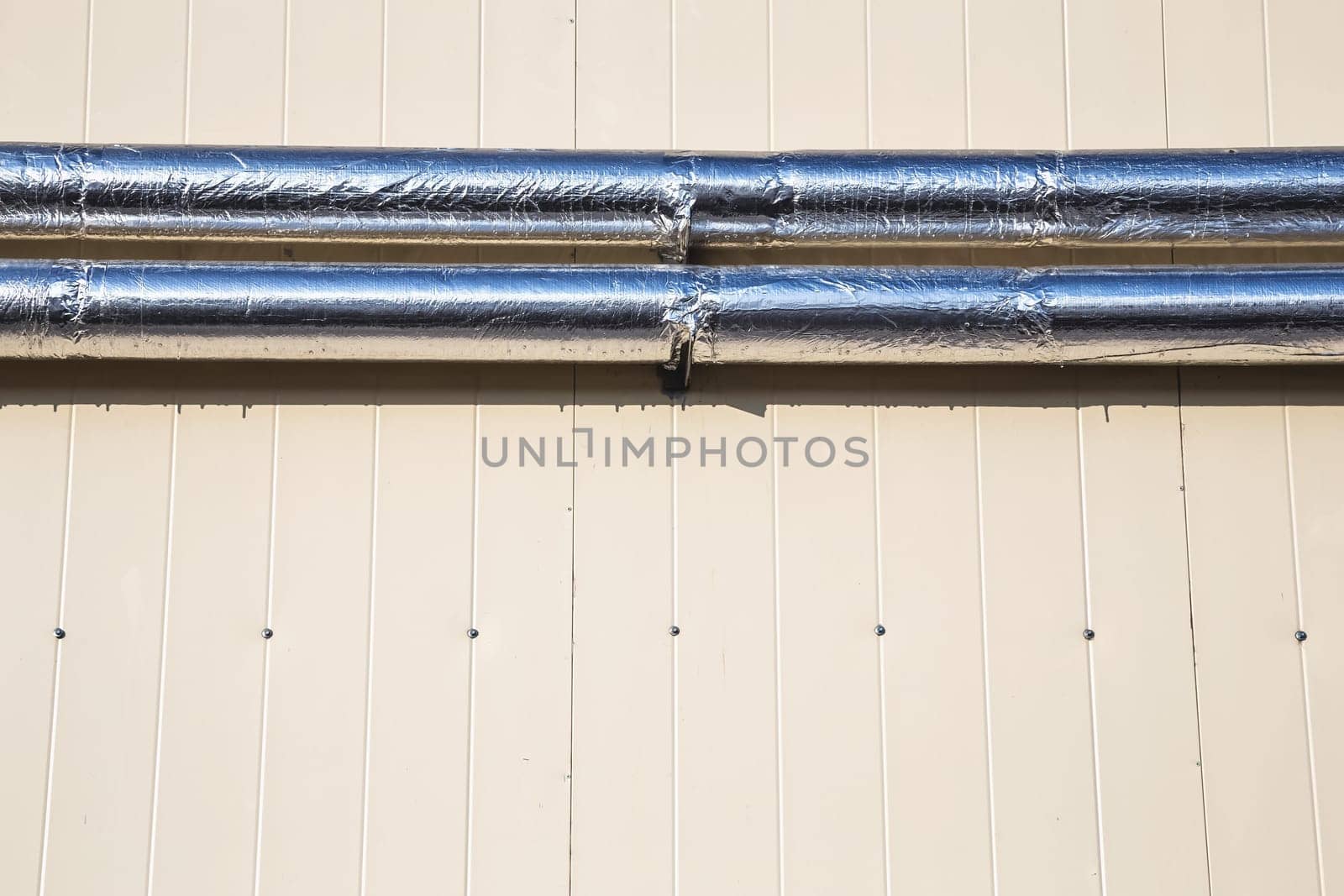 Metal chrome pipes on yellow plastic siding wall