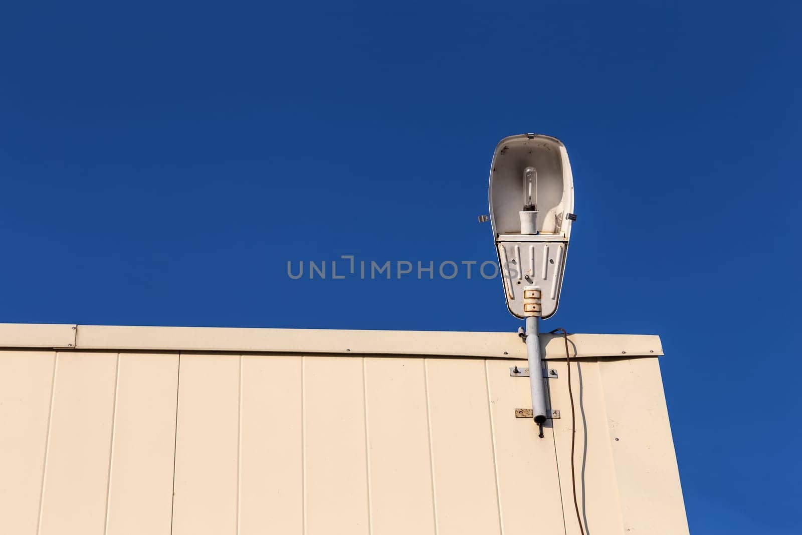 Old vintage lamp on rooftop against blue sky background
