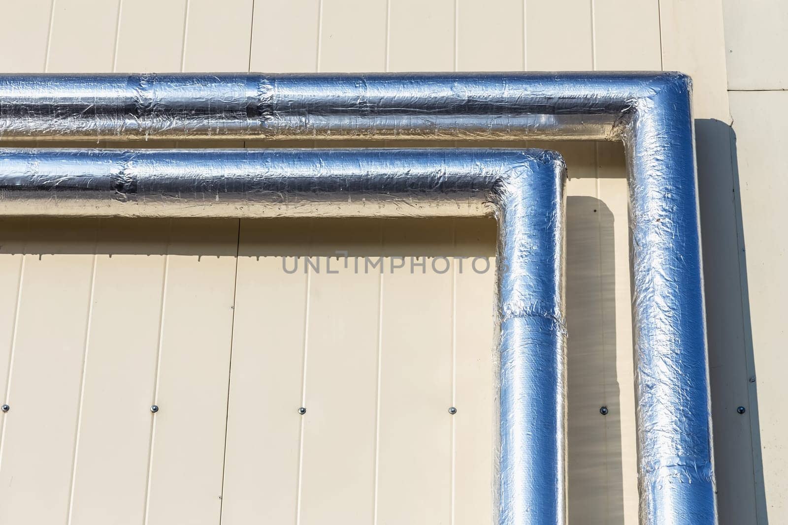 Metal chrome pipes on yellow plastic siding wall