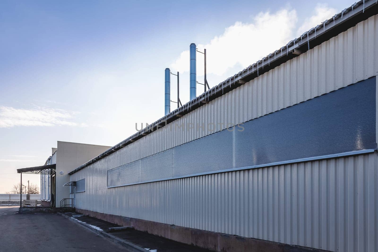 Plastic siding wall of industrial building with smoke pipes