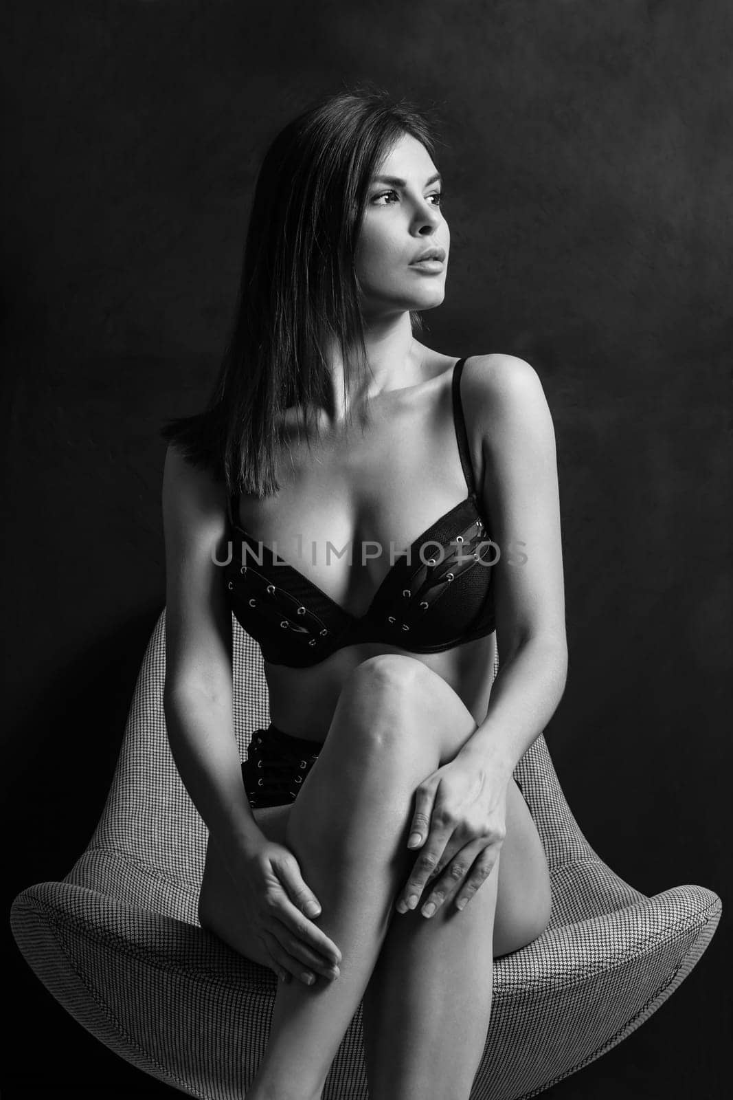 Sexy young woman posing in black underwear over a dark background.