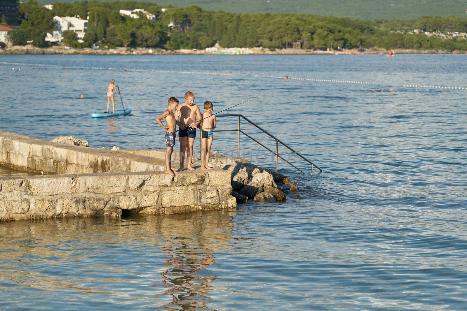 Fishing and bathing children on the coast of the town Krk on the Adriatic Sea in Croatia