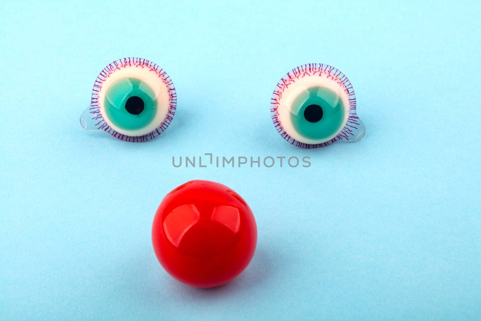 Decorative fruit candy eyes with red nose over light blue background. Conceptual photo using for funny celebration themes.
