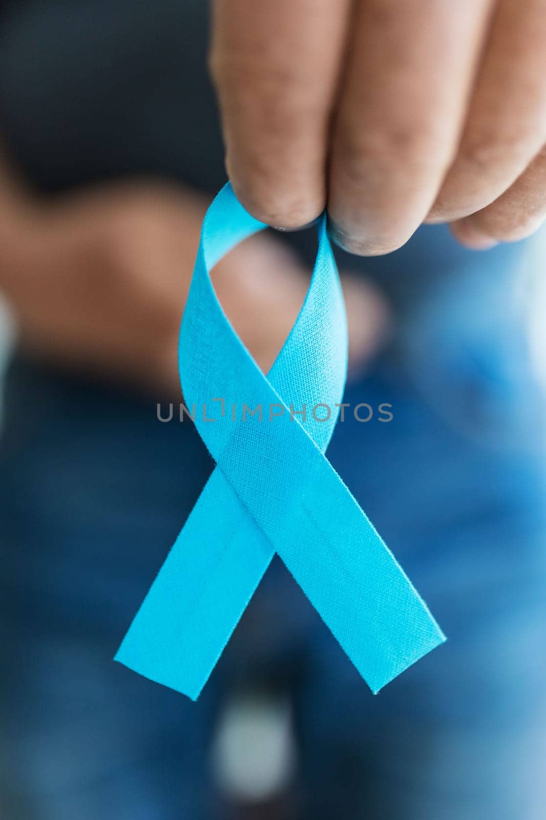 Senior man holding a blue cancer awareness ribbon in hand