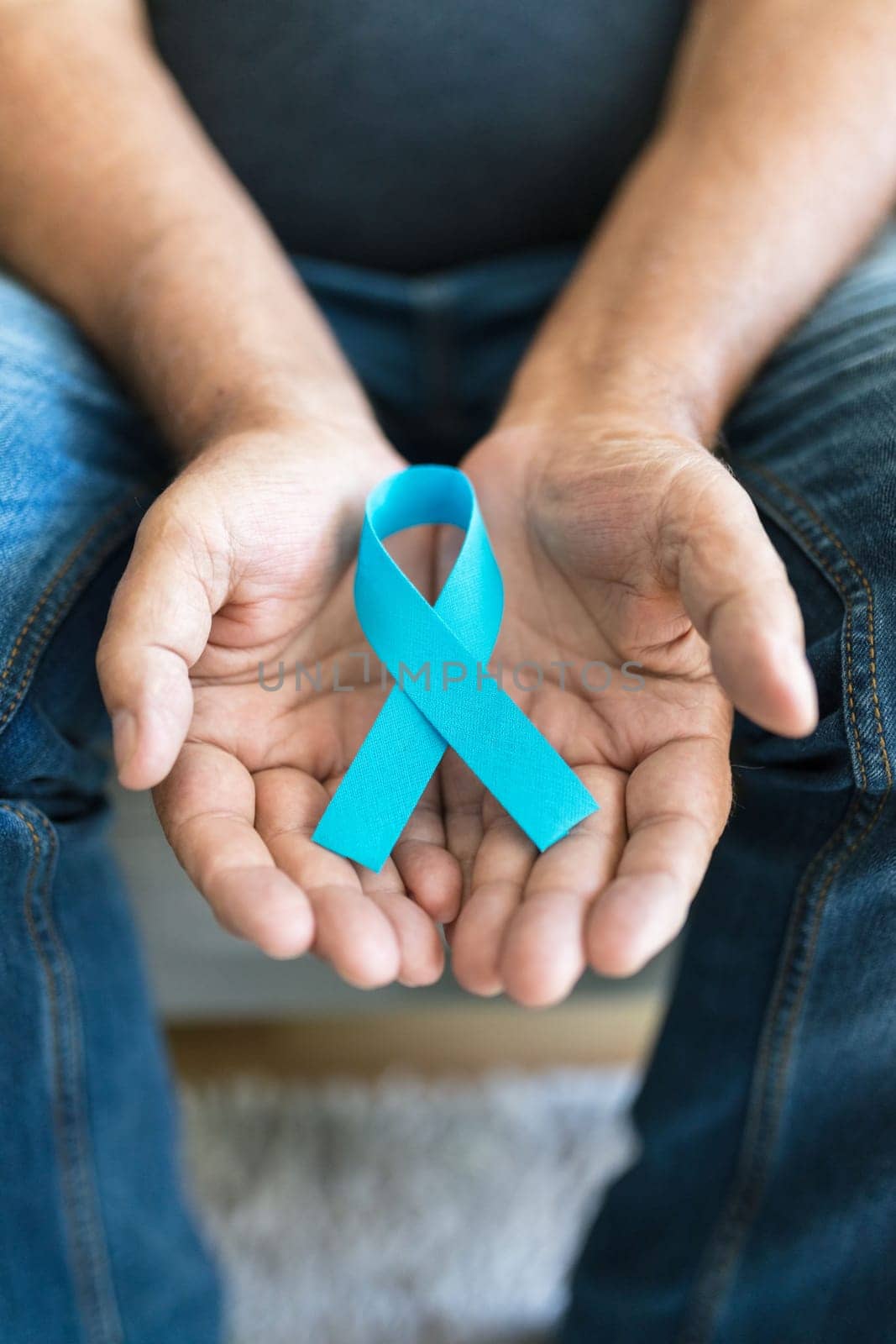 Senior man holding a blue cancer awareness ribbon in hand