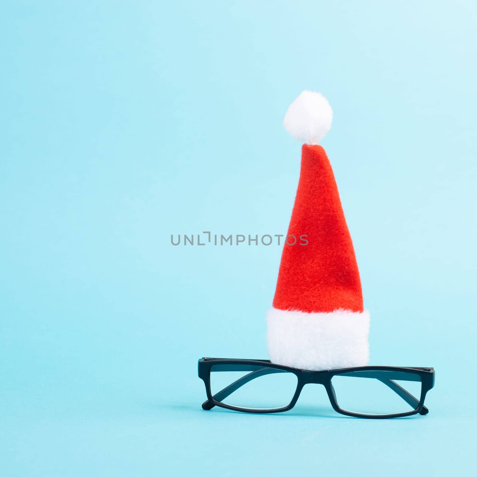 Christmas season, red Santa Claus hat and eyeglasses, funny face, winter time, holiday greeting card, blue background