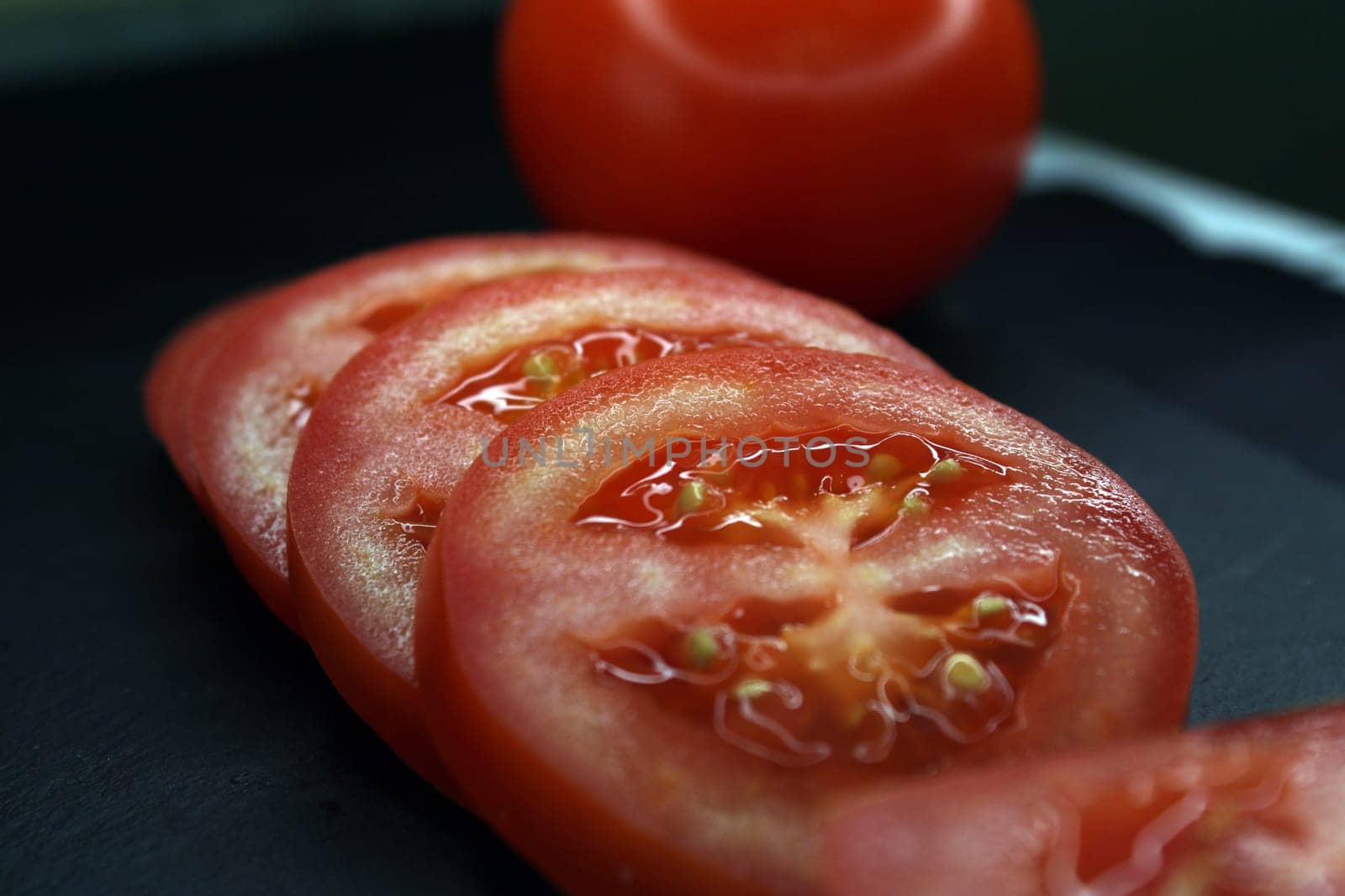 Tomato slices on a black background close-up. The concept of healthy eating..