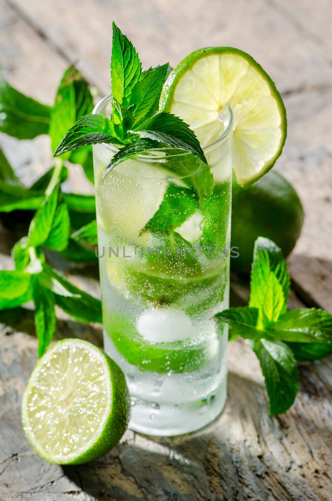 Mojito prepared with fresh ingredients on wooden table. Summer party cocktail recipe.