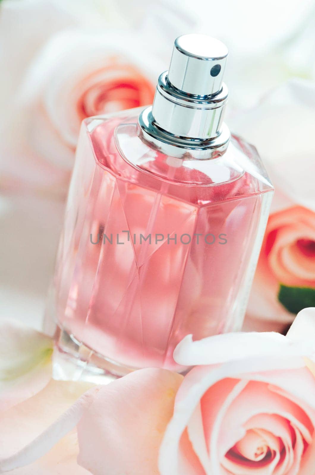 Luxury perfume bottle with pink roses petals. Fashion makeup and body care products.