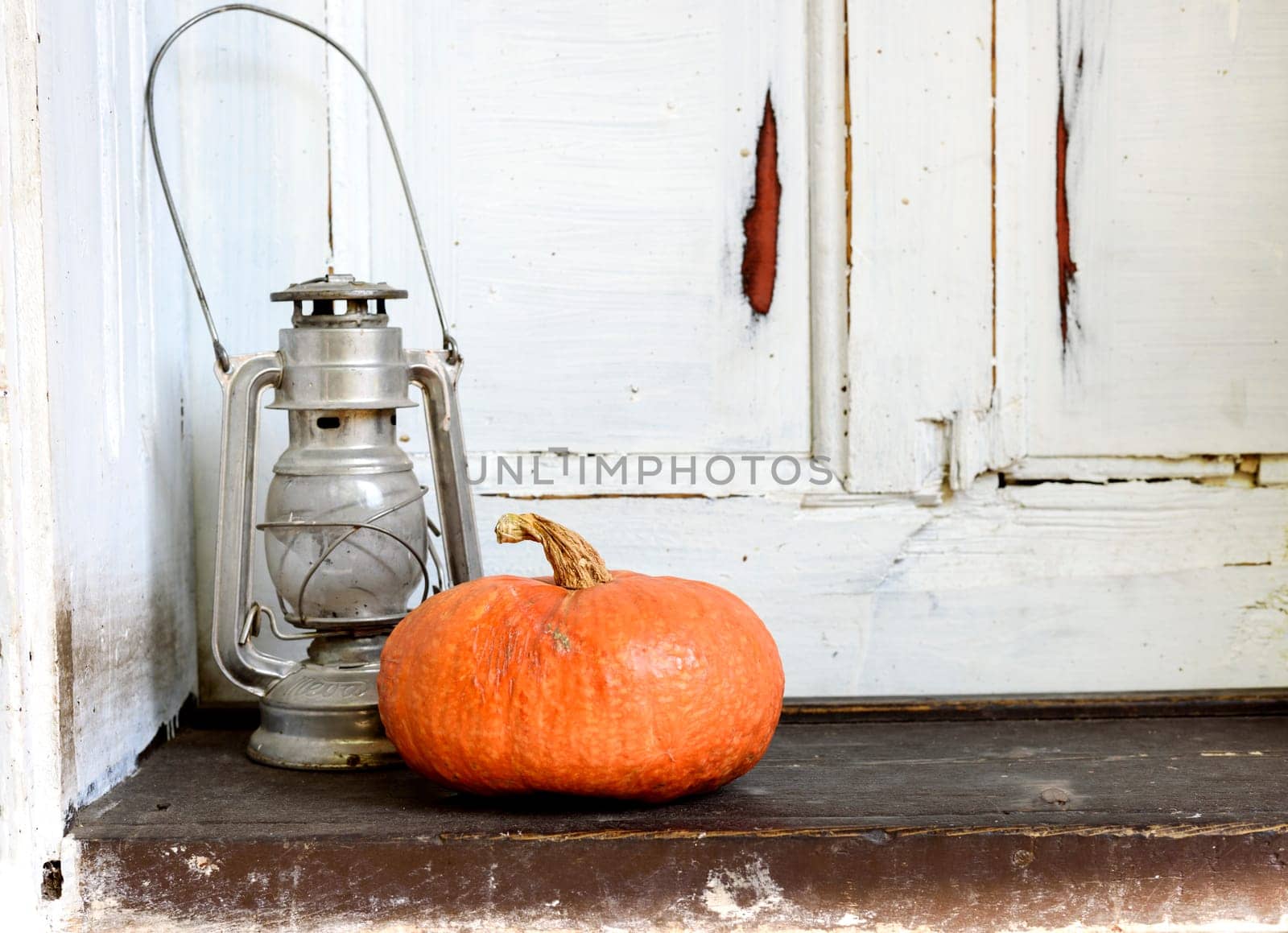Halloween pumpkin and old lantern on the grunge wooden background. Autumn concept still life.