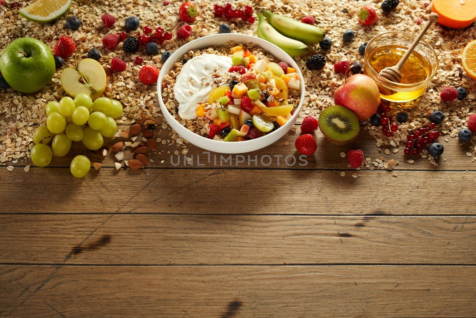 High angle of delicious oat with yogurt in bowl placed on table with arranged fruits and berries prepared for breakfast