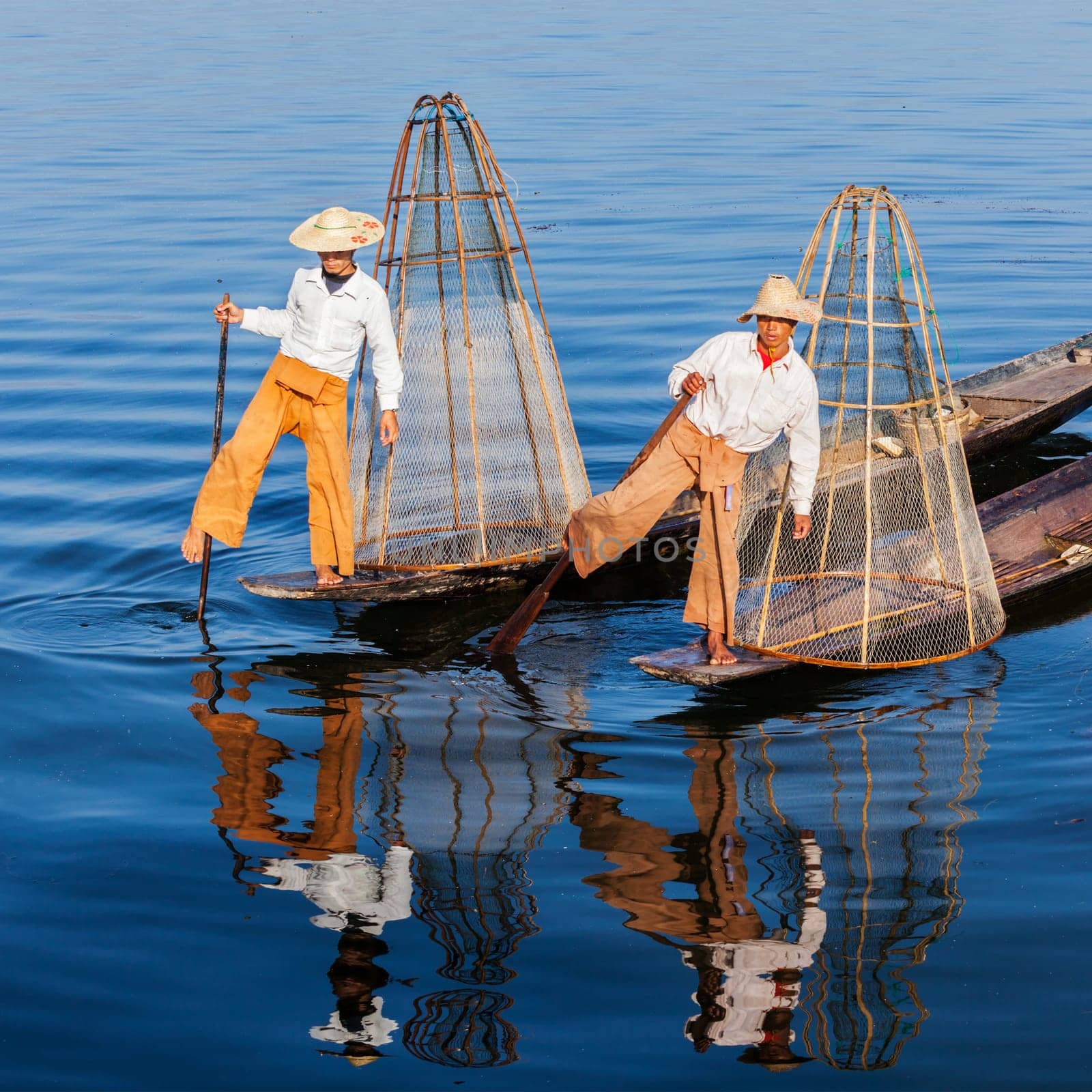 Myanmar travel attraction landmark - Traditional Burmese fishermen with fishing net at Inle lake in Myanmar famous for their distinctive one legged rowing style