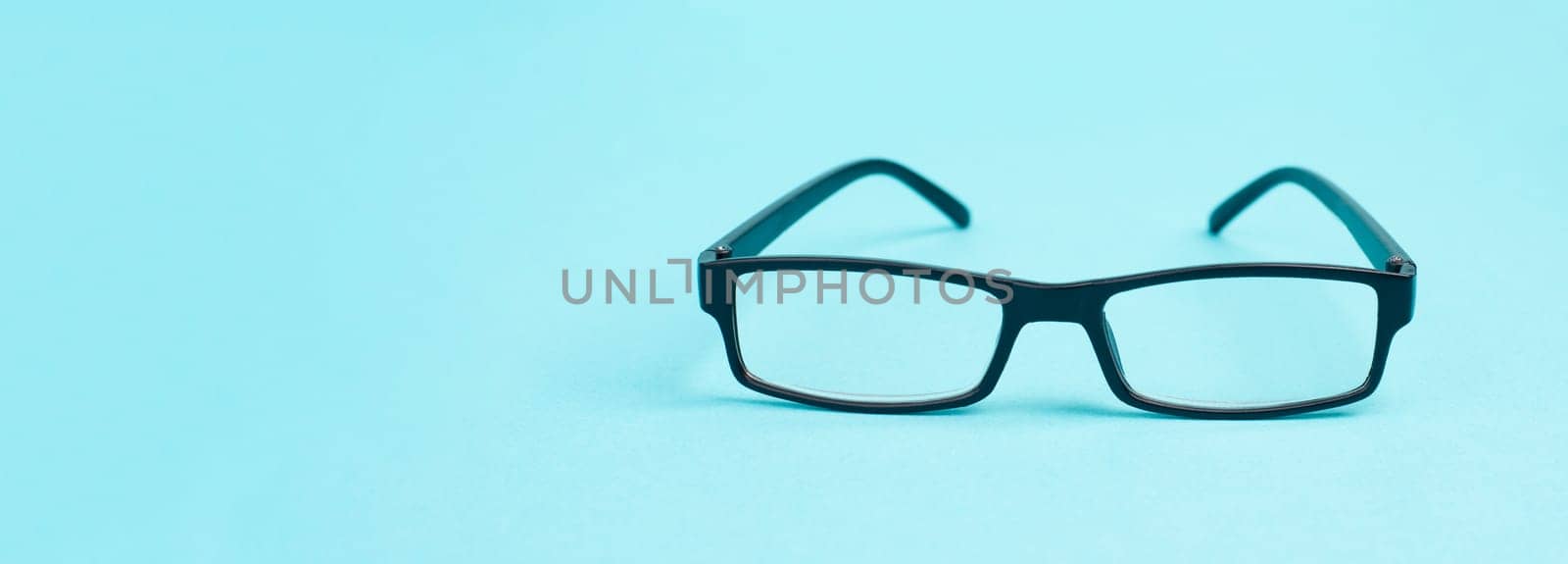 Glasses with a black frame on a blue background, copy space for text
