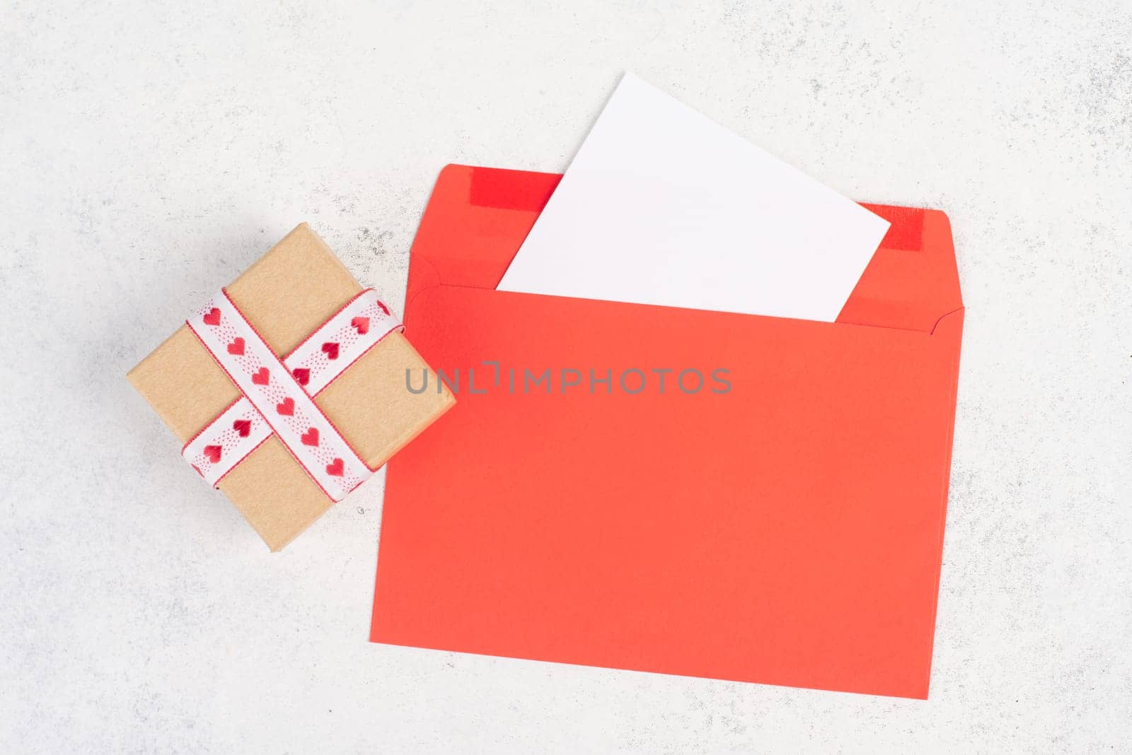 Red envelope with an empty paper, gift box with hearts, textured background, birthday, mothers day, fathers day and valintines day greeting card