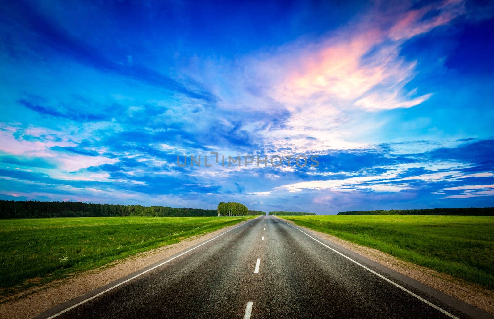 Travel concept background - road and stormy dramatic sky on sunset