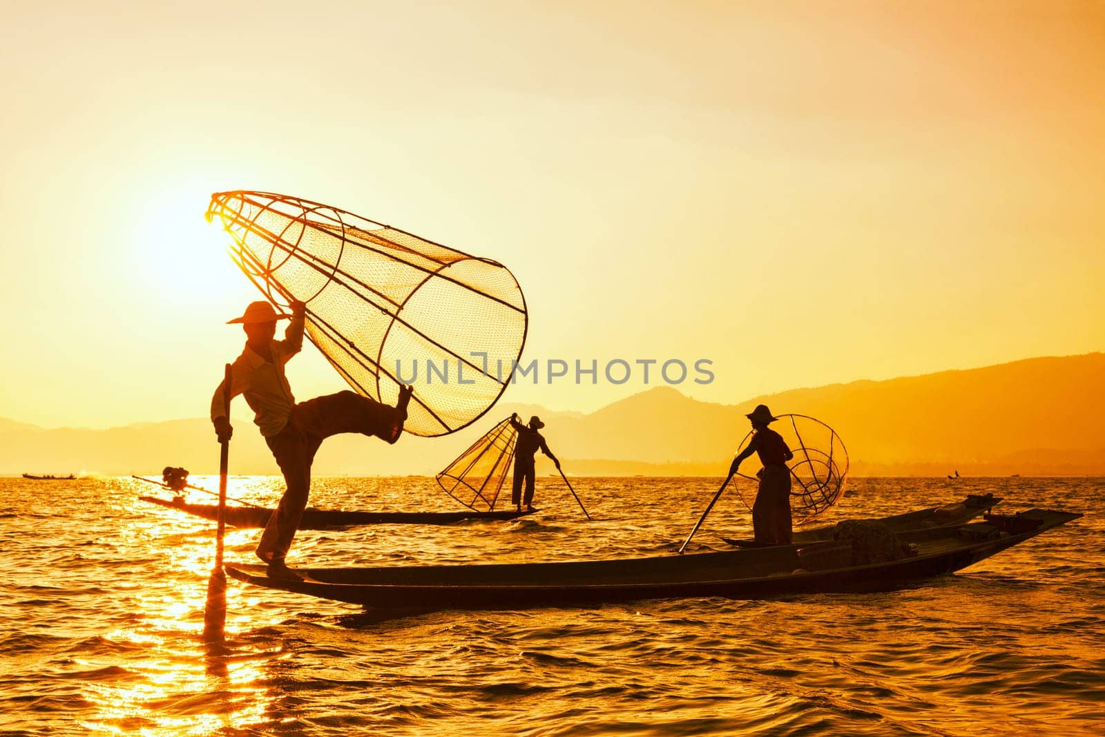 Vintage retro effect filtered hipster style image of Myanmar travel attraction. Traditional Burmese fisherman with fishing net at Inle lake famous for their distinctive one legged rowing style