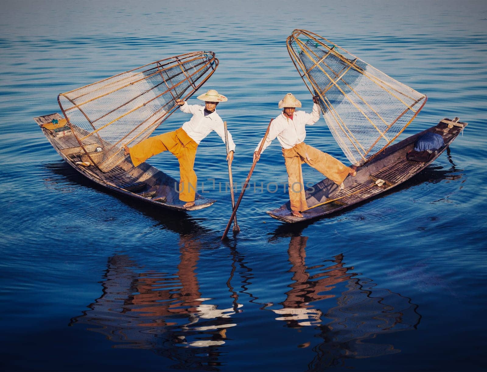 Myanmar travel attraction - Traditional Burmese fishermen balancing with fishing nets at Inle lake in Myanmar. Vintage filtered retro effect hipster style image