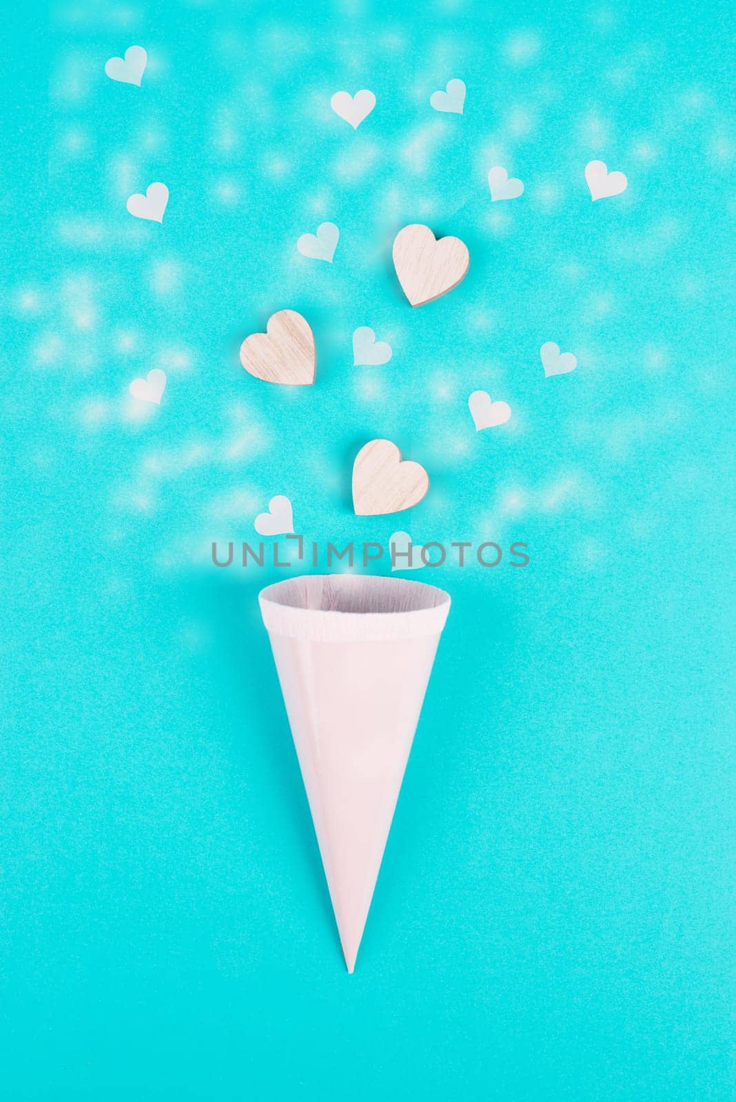 Cone with rose colored hearts, blue background, birthday and valentines day greeting card, spreading love, positive emotion, flat lay