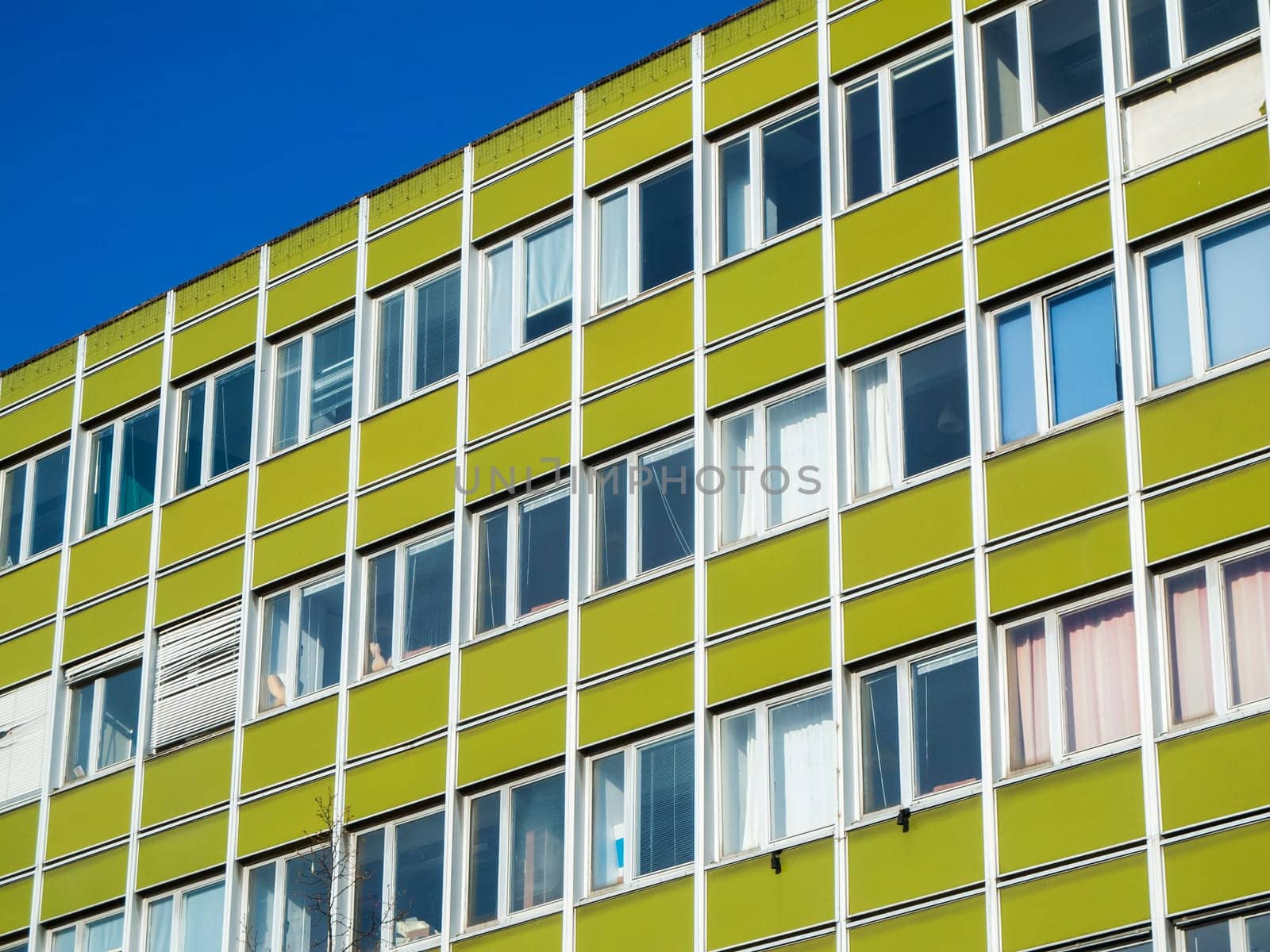 Oblique partial view of the facade of an older office building in a Berlin outskirts in front of a blue sky.