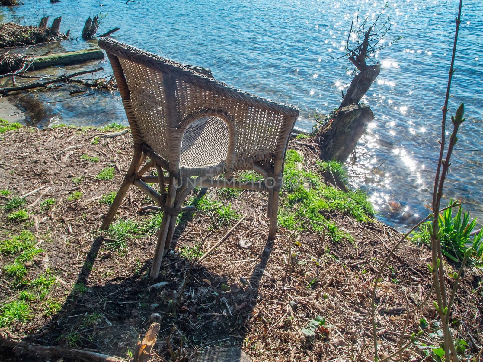 High angle view of a wicker chair on the shore of the Lake Flaken near Wolterddorf in Brandenburg in April 2022.