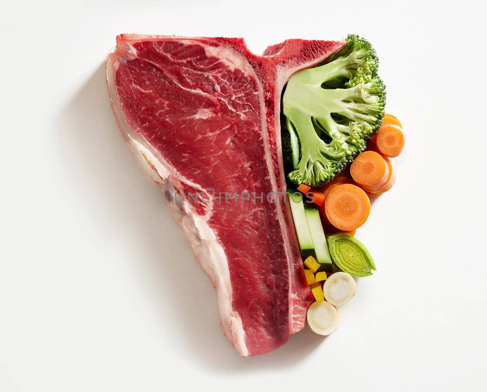 Half tbone steak on white background with carrots, cucumber, broccoli symbolic to eat more vegetables