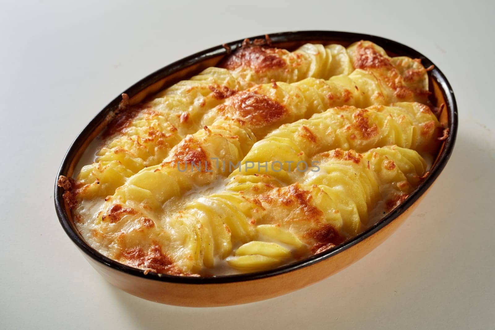 From above of casserole pan with appetizing traditional gratin au potato with cheese served on white table in kitchen