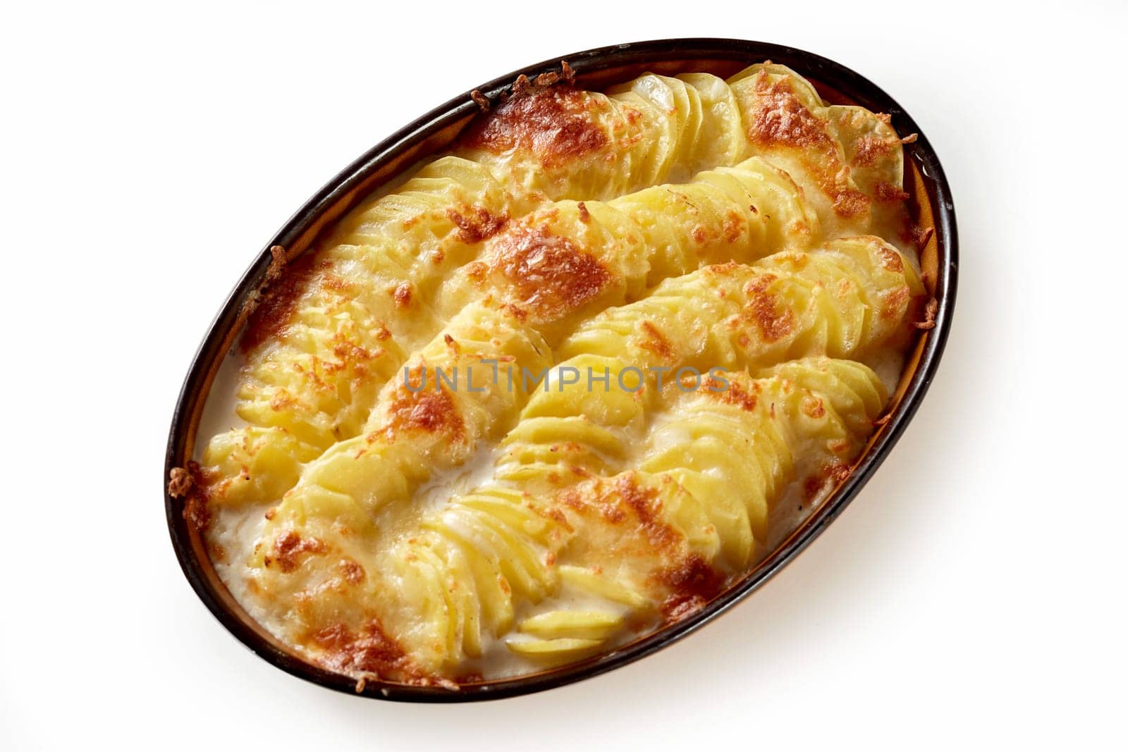 Tasty casserole dish with sliced potato and cheese in ceramic pan placed on white background