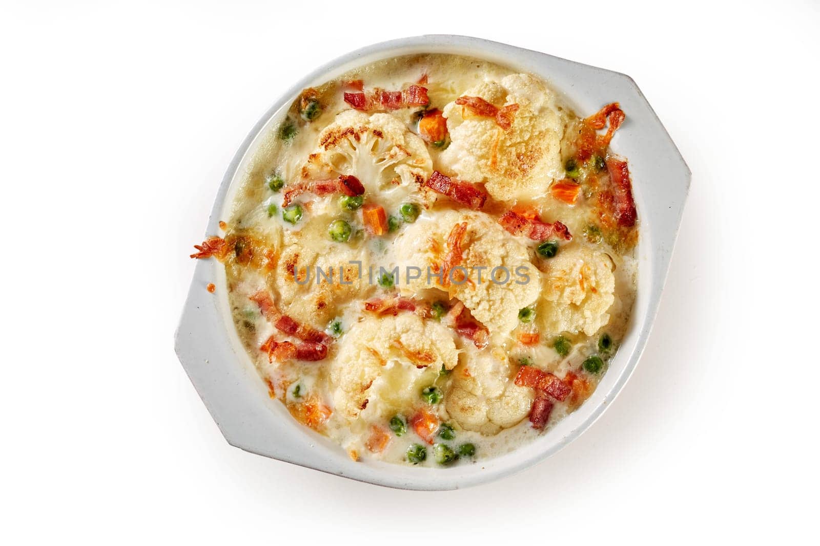 Overhead view of appetizing gratin made of cauliflower and vegetables and served in bowl on white isolated background