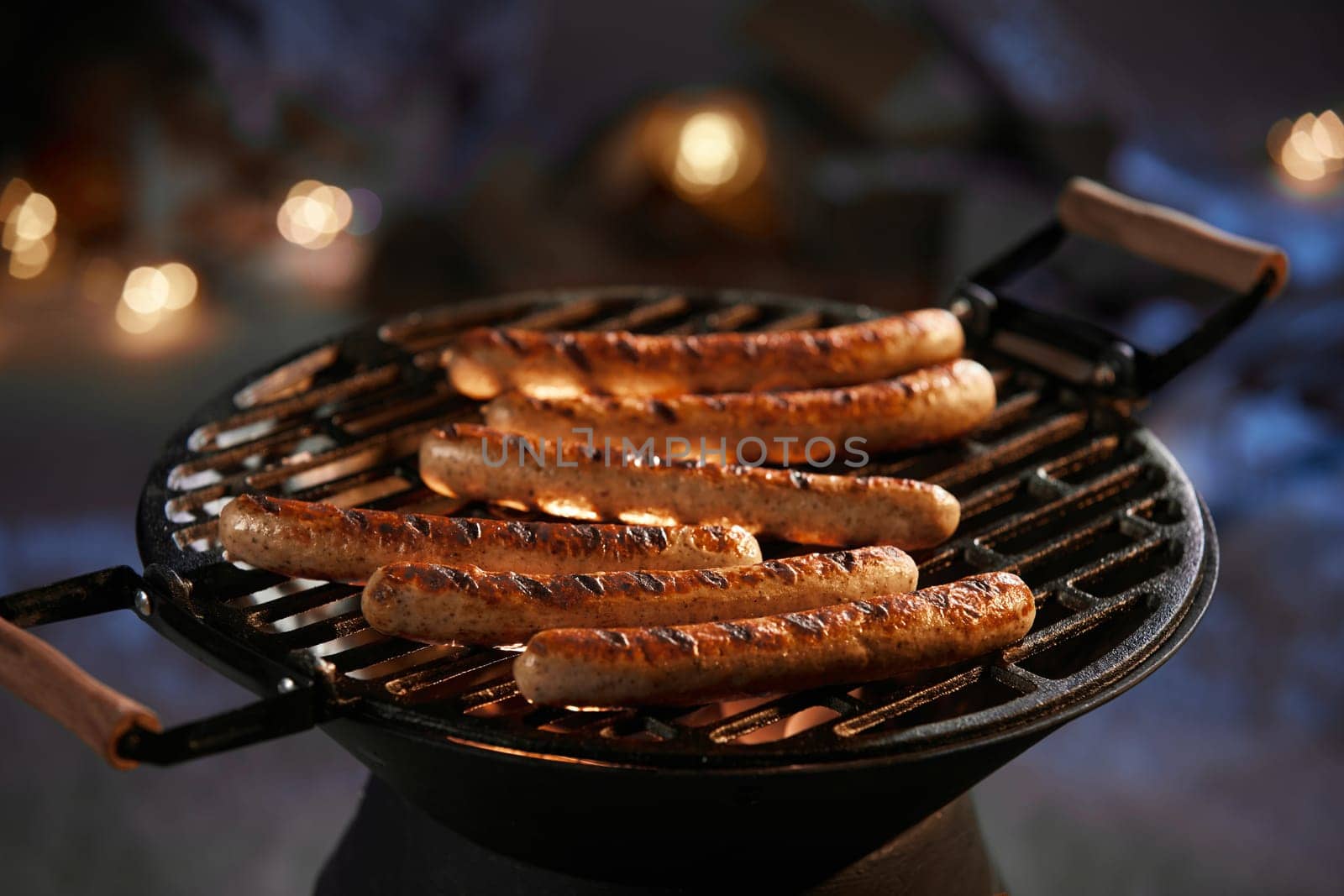 Delicious meat sausages preparing on barbecue for dinner on yard in dark winter night