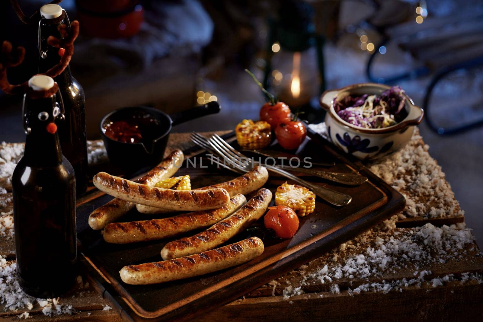 High angle of delicious grilled sausages corn and tomatoes served with sauce and cabbage salad for beer snacks at winter night