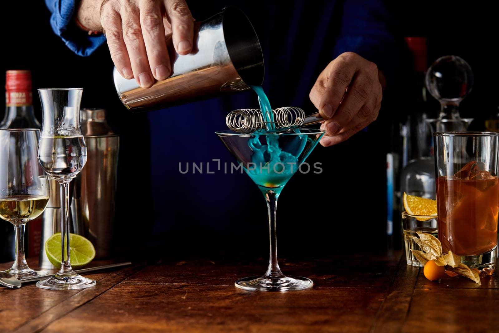 Crop unrecognizable barman pouting delicious Cinderella cocktail from metal shaker into glass while working in bar